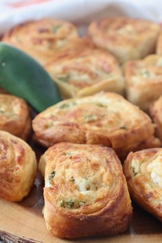 there are many small pastries on the wooden plate with a green leaf in the background