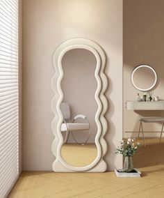 a large white mirror sitting on the side of a wall next to a table and chair