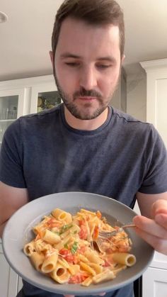 a man is holding a plate of pasta