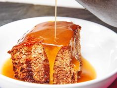 a piece of cake with caramel sauce being drizzled over it on a white plate