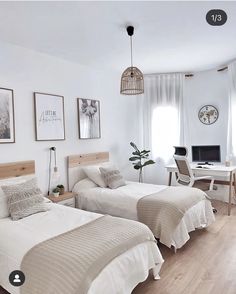 two beds in a room with white walls and wood floors, one has a computer on the desk