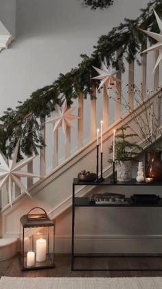 candles are lit in front of a staircase decorated with greenery and star garlands