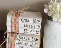 a stack of personalized coasters next to a vase with white flowers in it