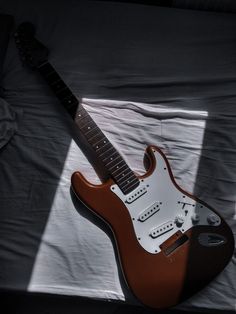 an electric guitar sitting on top of a bed