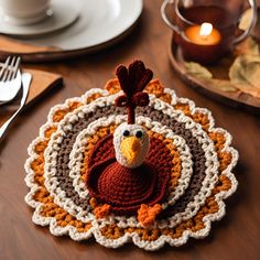 a crocheted turkey placemat sits on a table next to a cup and fork