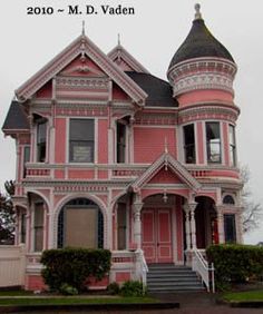 an old pink victorian house with black roof