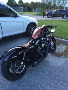 a black motorcycle parked next to a white car