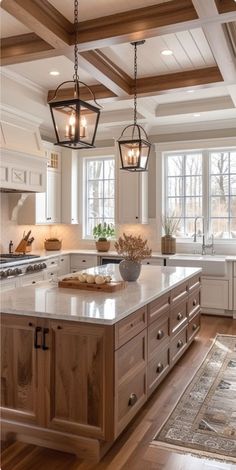 a large kitchen with an island in the center and two hanging lights over it's sink