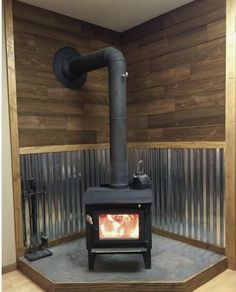 a wood burning stove sitting inside of a wooden room next to a metal pipe wall