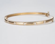 Our beautiful solid gold bezel-set diamond bangle bracelet is a timeless classic that's perfect for your wedding or anniversary, or to add as a family heirloom to your jewelry collection. It features a figure 8 locking hinge for extra security. Made with VS1 diamonds and available in 14k, 18k yellow, rose, white gold and platinum. This bracelet is fully customizable. If you prefer different size dimensions, or moissanites or colored gemstones, please contact us today to get started on a custom o Yellow Gold Channel Set Diamond Bracelet, Classic Channel Set Bangle For Anniversary, Classic Yellow Gold Bangle With Brilliant Cut, Classic Yellow Gold Diamond Bangle, Classic Formal Bangle With Channel Set, Classic Channel Set Round Bangle, Yellow Gold Diamond Bracelet With Bezel Setting For Wedding, Classic Gold Bangle Bracelet With Diamond Accents, Formal Yellow Gold Bangle With Bezel Setting