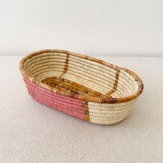 a woven basket sitting on top of a white table next to a red and yellow object