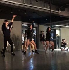 a group of young people dancing in a dance studio with one woman holding her hand up