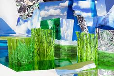 an abstract painting with green grass and blue sky in the background, surrounded by cut out pieces of paper