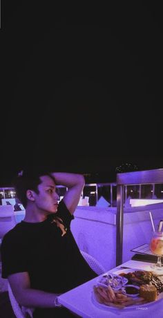 a man sitting at a table with food and drinks in front of him on a boat