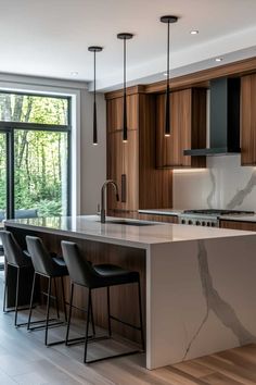 a modern kitchen with marble counter tops and black chairs in front of an open window