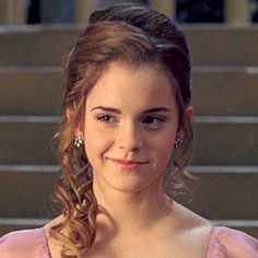 a woman in a pink dress is smiling at the camera