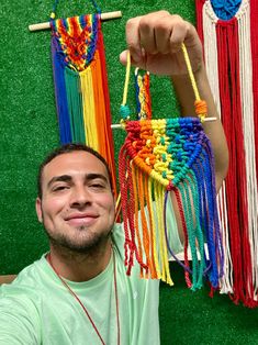 a man is smiling while holding up some colorful beads on a string and sticks in front of him