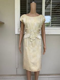 Get ready to turn heads in this stunning vintage gold metallic brocade wiggle cocktail frock from the 50s/60s. The bodycon style and knee-length hemline make it perfect for a party or cocktail occasion, while the intricate brocade material adds a touch of elegance and sophistication. This dress is a size small and has a regular fit, making it ideal for women who want to show off their curves. The 60s theme and timeless design make it a versatile addition to any wardrobe. Don't miss out on this g Chic Fitted Brocade Dress, Formal Gold Brocade Dress, Vintage Brocade Party Dress, Fitted Knee-length Dress For Vintage Events, Vintage Champagne Party Dress, Vintage Brocade Fitted Dress, Vintage Fitted Gold Dress, Vintage Sheath Dress For Formal Occasions, Vintage Gold Dress For Vintage Events