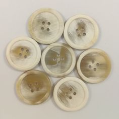 six buttons with holes in them on a white surface