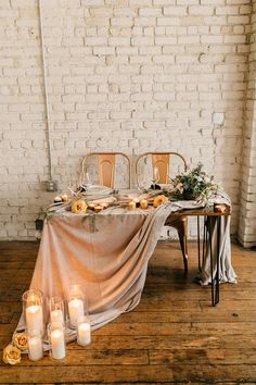 the table is set with candles and flowers for an elegant wedding reception in white brick walls