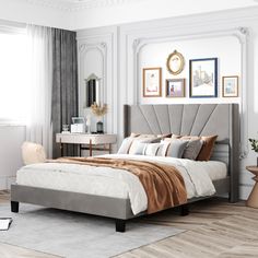 a bedroom with white walls and wood flooring has a large bed in the middle