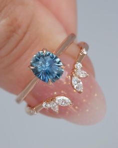 a woman's hand holding two rings with a blue topazte and white diamonds