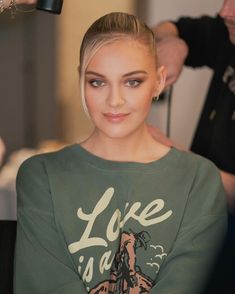 a woman is getting her hair styled