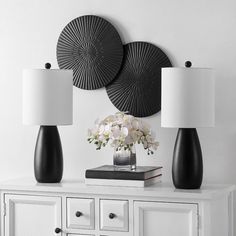 two black and white lamps on top of a dresser