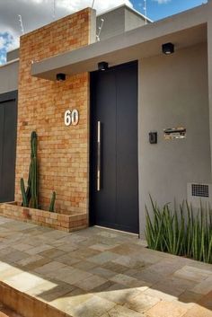 a brick building with two black doors and a cactus plant in front of the door