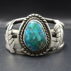 "VINTAGE NAVAJO BRACELET DESCRIPTION: This classic vintage Navajo cuff features a glorious specimen of medium to deep blue-green turquoise. The gemstone is secure in smooth bezel, on a foundation of heavy gauge vintage sterling silver. Applied leaves flank the turquoise cabochon. This bracelet will be a cherished addition to your collection of fine vintage Native American jewelry. MEASUREMENTS: Interior of the cuff measures 5 1/4\" with an additional 1 1/4\" slightly adjustable gap. Total circum Vintage Gemstone Cuff Bracelet Collectible, Blue Oval Vintage Cuff Bracelet, Classic Adjustable Turquoise Ring, Classic Turquoise Cuff Bracelet Gift, Classic Adjustable Turquoise Cuff Bracelet, Vintage Sterling Silver Cuff Bracelet With Patina, Morenci Turquoise, Bisbee Turquoise, Bones Bracelet