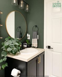 a bathroom with green walls and a round mirror on the wall above the sink is a plant