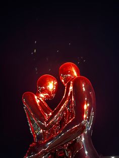 two people sitting on the back of a shiny motorcycle at night with their arms around each other