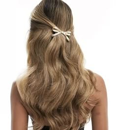 the back of a woman's head with long hair and a bow in it