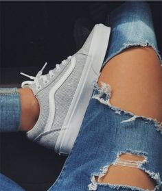 a woman's legs with ripped jeans and white vans on them, in front of a poster for poshmark