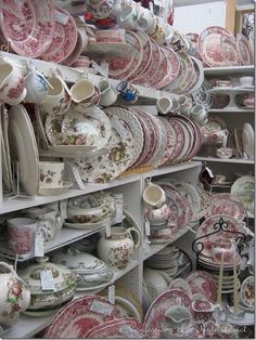 many plates and bowls are on shelves in a store, some have been stacked high