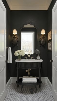 a black and white bathroom with two sinks, mirrors and flowers in vases on the counter