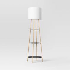 a white lamp sitting on top of a wooden floor next to a black and white shelf