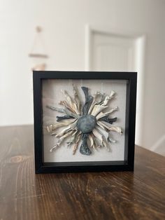 a shadow frame with an image of a sunflower in it on top of a wooden table