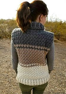 a woman standing in the dirt with her back to the camera, wearing a gray sweater and green pants