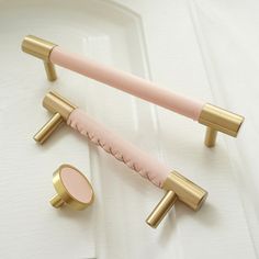 two pink and gold bathroom accessories on a white surface