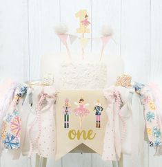 a birthday cake on a chair with ribbons around it and an one sign hanging from the back