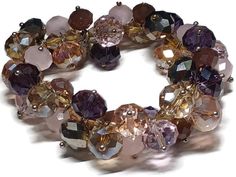 This bracelet has various shades of dark purple, lavender, and milky light purple. It measures 8 inches long by 1 inch wide. If you are someone who loves purple, this bracelet is for you! Purple Stretch Bracelet With Round Beads For Party, Purple Round Bead Crystal Bracelet For Parties, Purple Round Beads Crystal Bracelet For Party, Purple Round Beaded Crystal Bracelet For Parties, Purple Crystal Round Beads Bracelet For Party, Purple Beaded Bangle Bracelets For Party, Cluster Bracelets, Brown Jewelry, Stylish Work Outfits