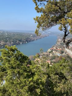 a scenic view of the water and trees from atop a hill with houses on it