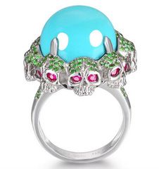 a ring with three skulls on it and two pink, green and white stones in the middle