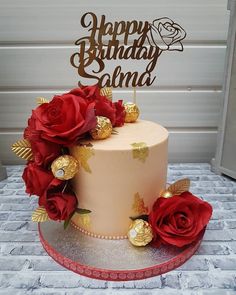 a birthday cake with red roses and gold decorations