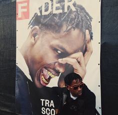 a man standing in front of a poster with dreadlocks on his face and mouth