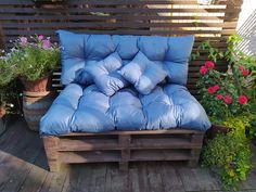 a couch made out of wooden pallets with pillows on it and flowers in the background