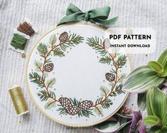 an embroidery pattern with pine cones and evergreen needles on it, surrounded by other items