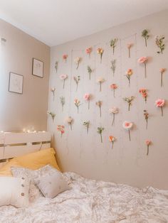 a white bed topped with lots of flowers next to a wall mounted on it's side