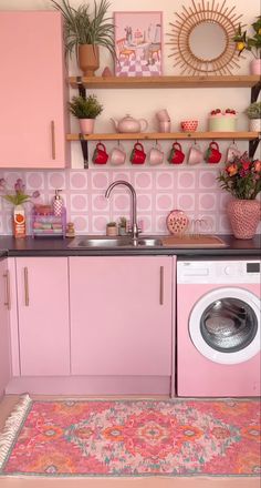 a kitchen with pink cabinets and an area rug that matches the sink, countertop, and washer / dryer